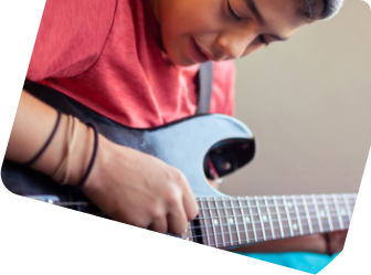 Ein Jugendlicher spielt auf einer schwarzen Gitarre.