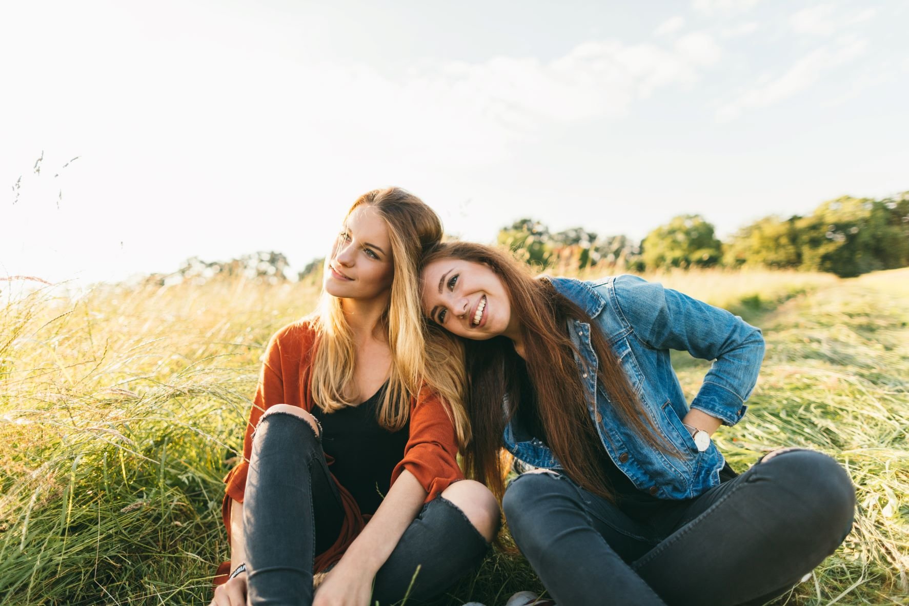 Zwei junge Frauen sitzen zufrieden auf einer Wiese.